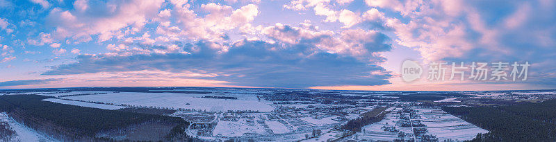鸟瞰图的冬天下雪的乡村在日落。水平全景