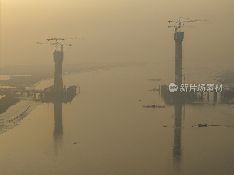 日出时正在施工的跨海大桥建筑工地的航空照片