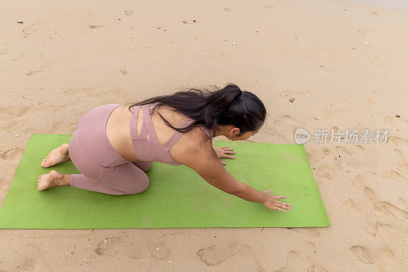 一名泰国妇女在阴天的海边练习瑜伽，找到了宁静