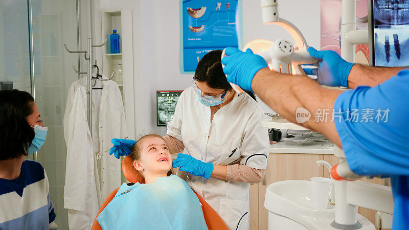 牙医用镜子检查小女孩病人的牙齿健康