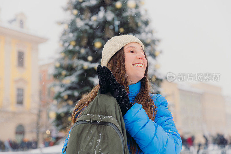 快乐的女人背着背包，在克拉科夫思考下雪的圣诞节