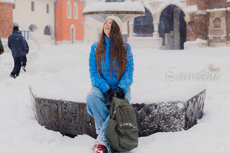 快乐的女人背着背包，在克拉科夫思考下雪的圣诞节