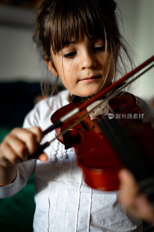 年幼的孩子，刚上小学的女孩在练习拉小提琴