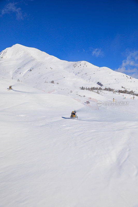 用造雪枪造雪。滑雪坡人工下雪。滑雪场配有雪炮-造雪机。美丽的冬季大自然。山顶上的新雪。高山景观滑雪场。