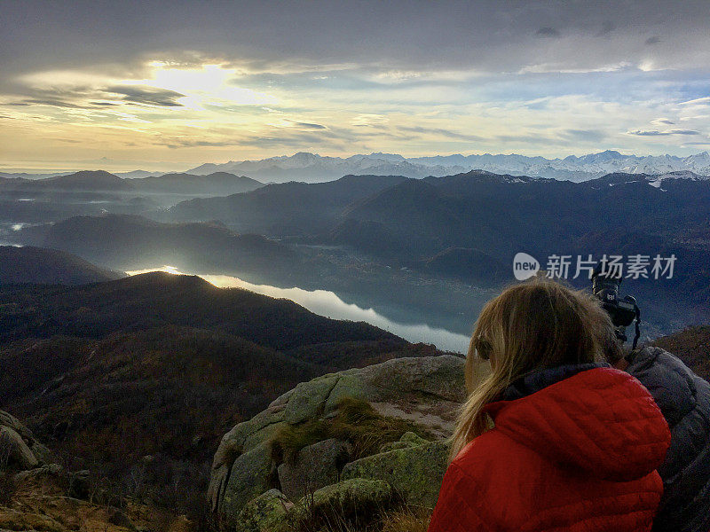 年轻女子兼摄影师在湖上的山上