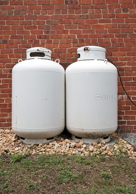 两罐丙烷罐靠在砖墙上