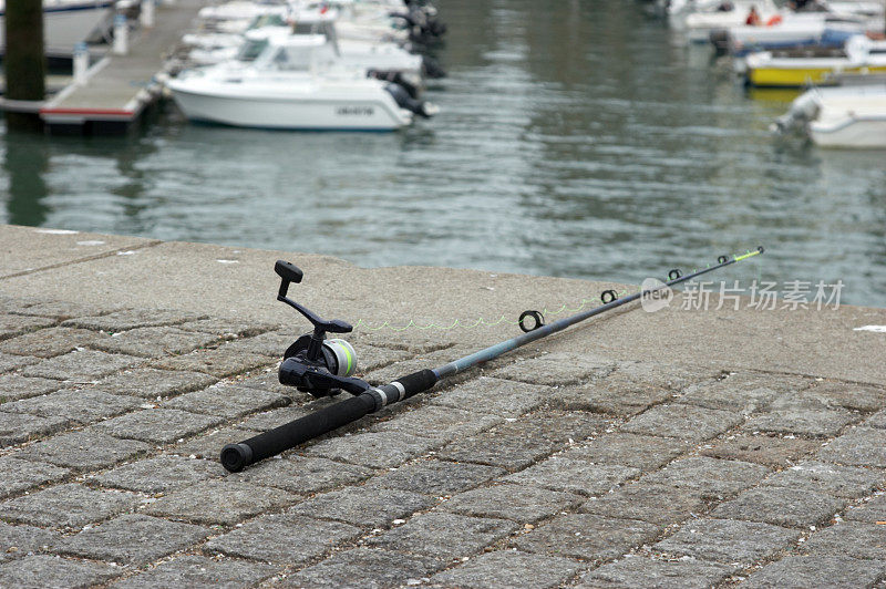 鱼竿和卷轴挂在海港的壁上