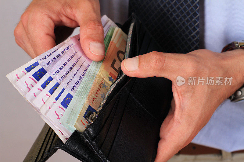 一名男子从装满欧元钞票的钱包里拿出钱。