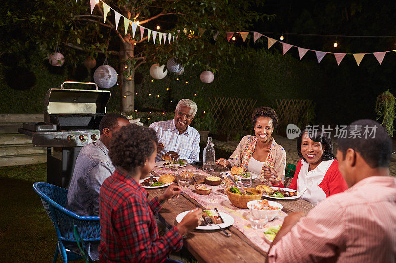 成年黑人家庭在他们的花园里一起享用晚餐