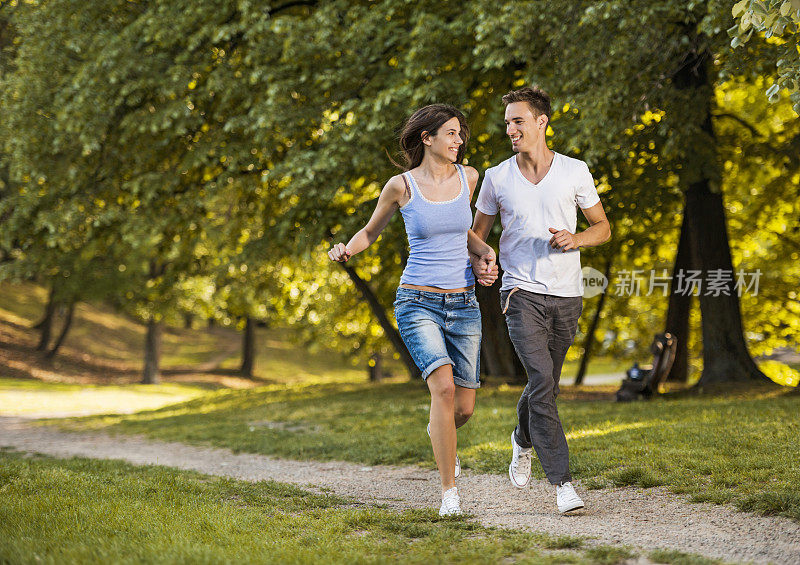 一对快乐的情侣在公园里跑步。