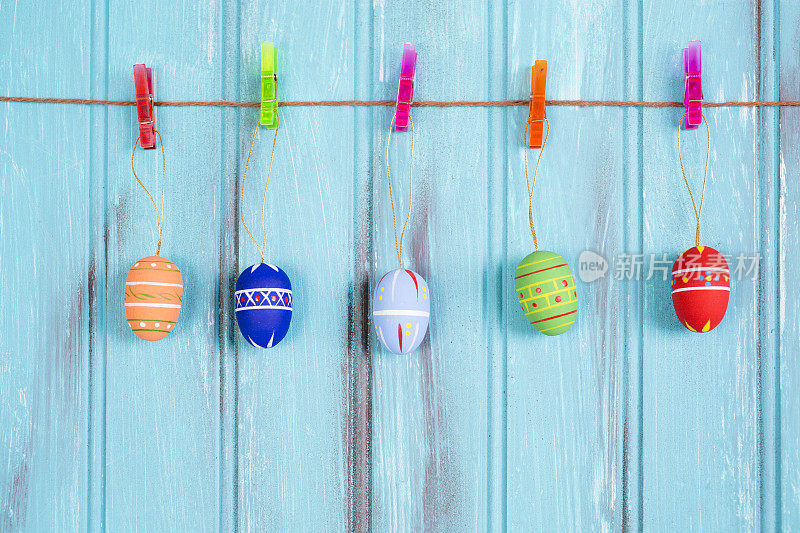 复活节彩蛋的装饰品挂在蓝木头上。季节性的背景。