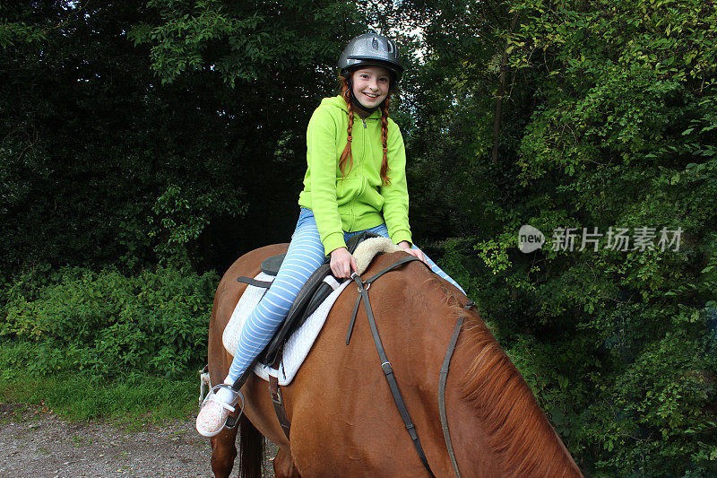 小女孩享受着骑马课，戴着骑马帽