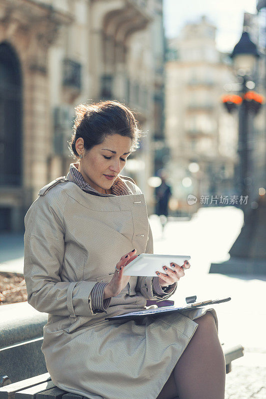 一位坐着用平板电脑打字的女商人