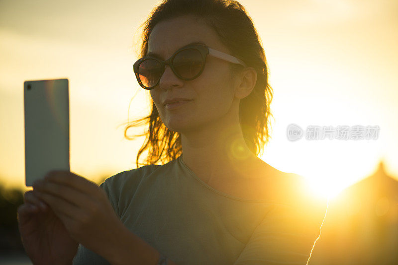 一名女子在夕阳下自拍。