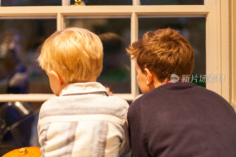 夜幕降临，两个男孩望着窗外