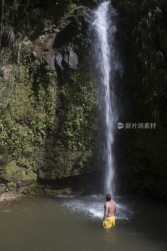 在热带瀑布洗澡的男人