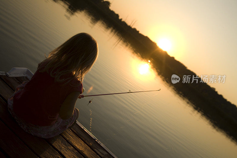 小女孩在夕阳下钓鱼