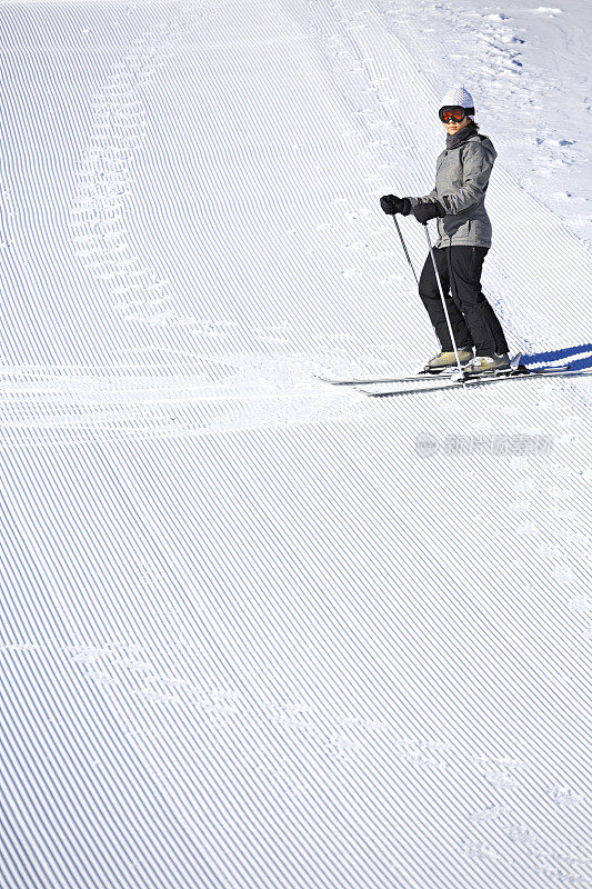 女滑雪者享受在完美准备的滑雪斜坡上休息