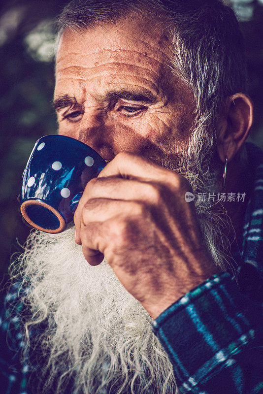 一个长胡子的男人在户外喝咖啡的肖像