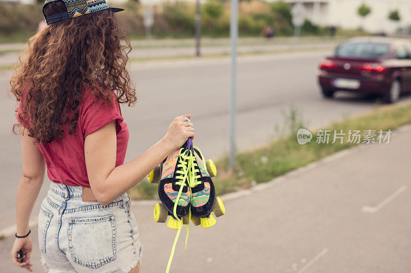 照片的轮滑性感的女人拿着她的溜冰鞋的鞋带，户外