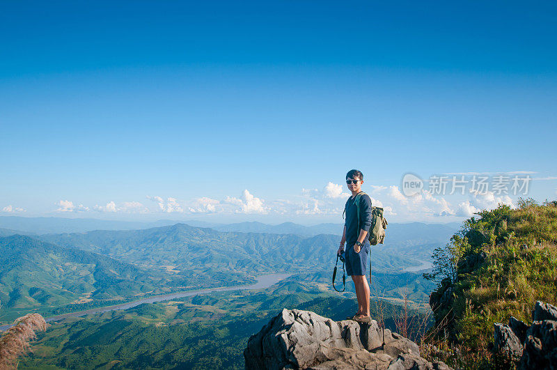 年轻的旅行者站在山上望着夕阳。