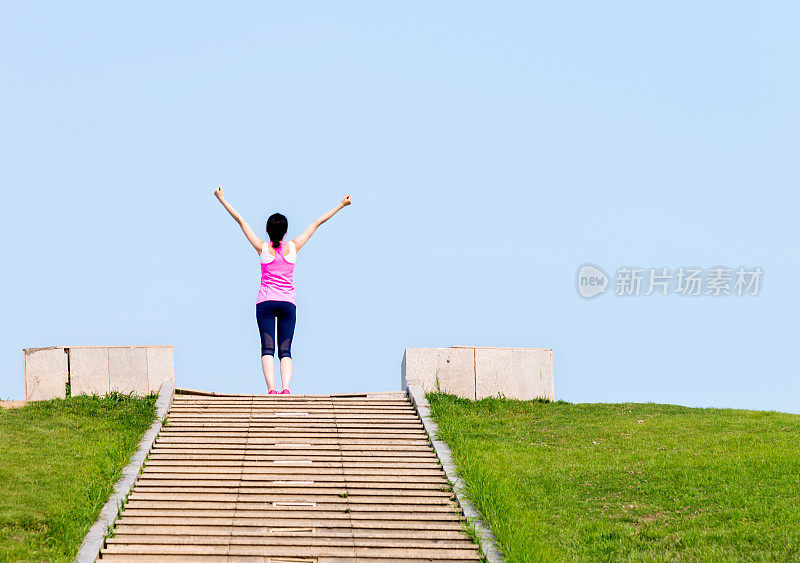 一个年轻女子在楼梯间的顶端举起双手