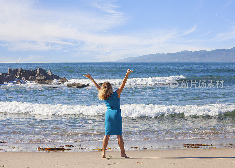 自由-在海滩上举起手臂的女人