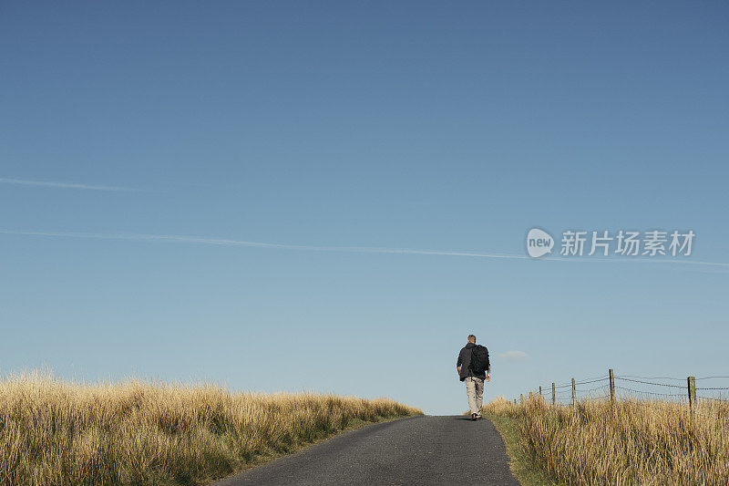 一个背着背包走在偏远乡村路上的人。