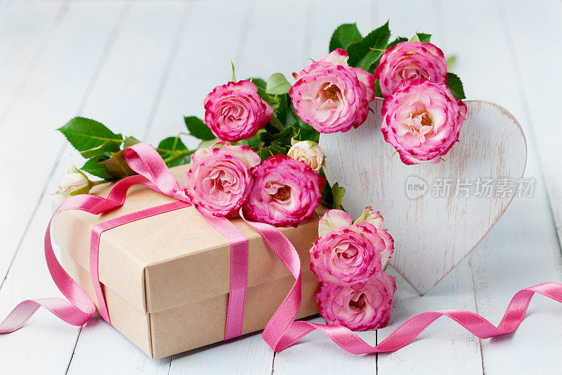 蓝色质朴的桌子上放着玫瑰花、木心和礼盒。美丽的生日贺卡，女人或母亲节。