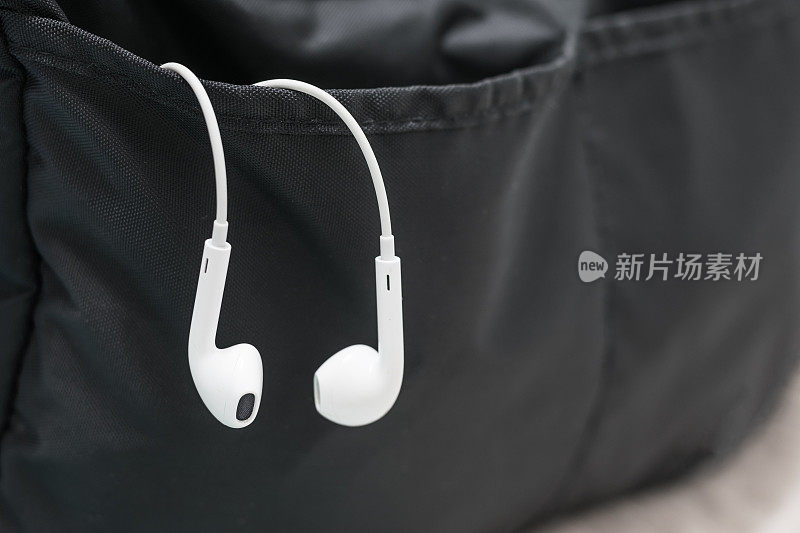 一副耳机挂在一个黑包里。用于配件听音乐和手机或智能手机聊天和放松。