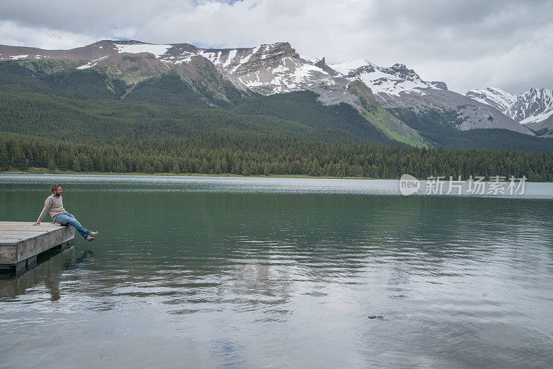 年轻人在湖边码头上看山景