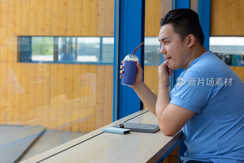 年轻英俊的亚洲男子放松在咖啡店