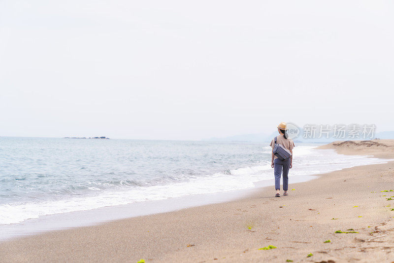 一位女旅行者在海滩上散步