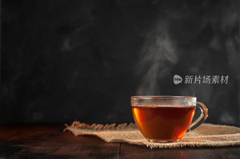 一杯新泡的红茶，逸出蒸汽，温暖柔和的光线，较暗的背景。