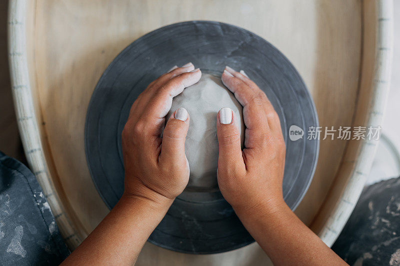 女陶工的双手，准备在陶轮上用白粘土工作