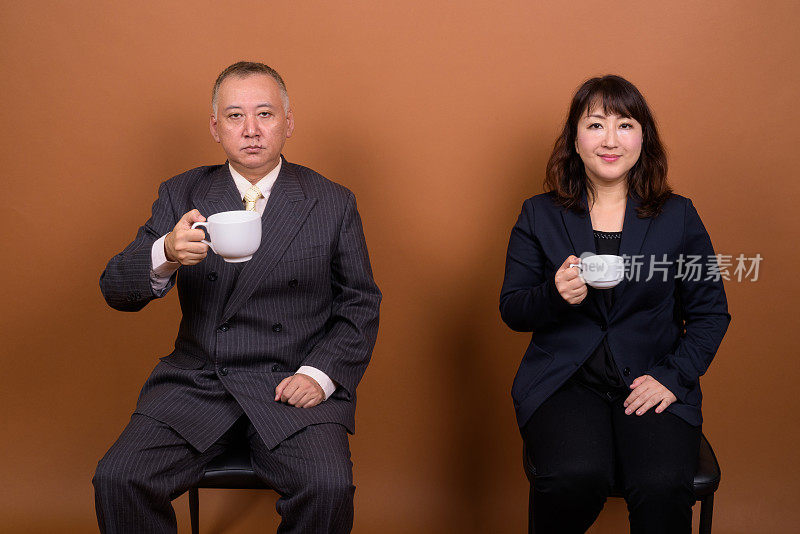 工作室拍摄了两个成熟的亚洲商人和女商人的彩色背景
