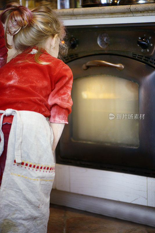 小女孩在烤箱里烤蛋糕