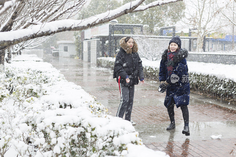 女性朋友穿着暖和的衣服在雪地里玩