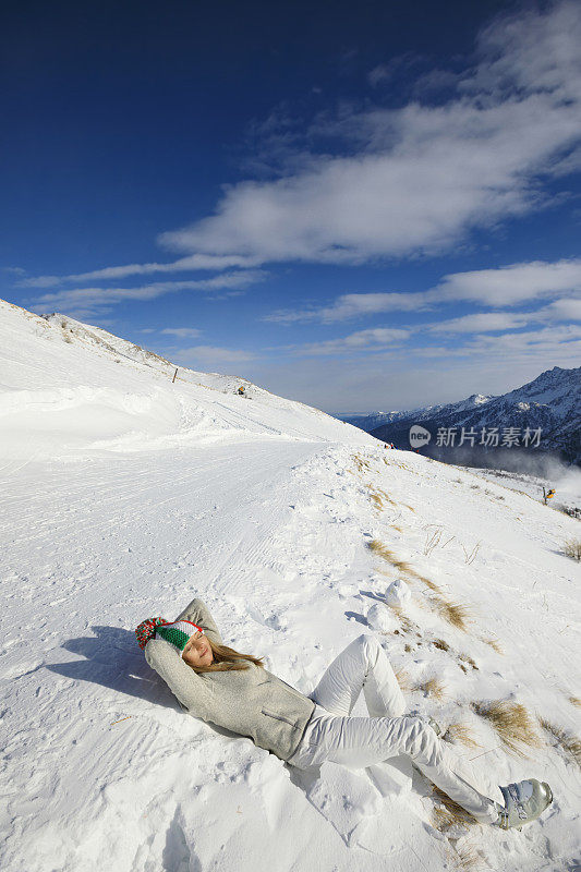 女人，滑雪者日光浴，躺在地上，享受阳光明媚的滑雪胜地。高山雪景。意大利阿尔卑斯山脉的白云石意大利，欧洲。业余的冬季运动。