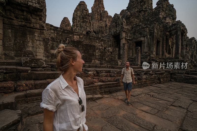 一对在亚洲旅游的游客，在夕阳下凝视美丽的古庙和古老的废墟;人发现探索理念