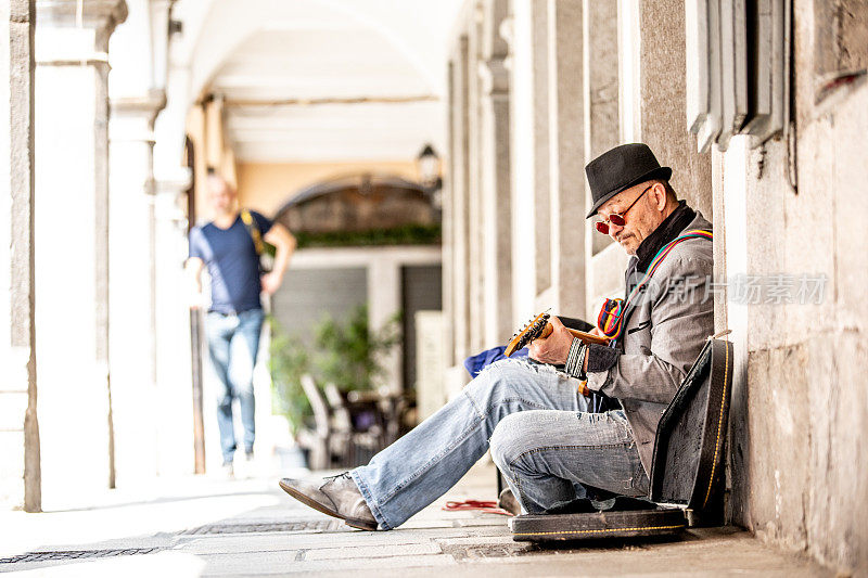 在城市街道上弹吉他的资深街头表演者