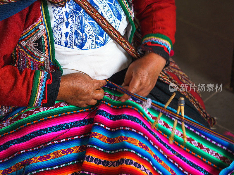 秘鲁妇女的手使羊驼毛地毯与民族图案的特写。秘鲁库斯科生产羊毛材料。身着鲜艳传统秘鲁服饰的女子