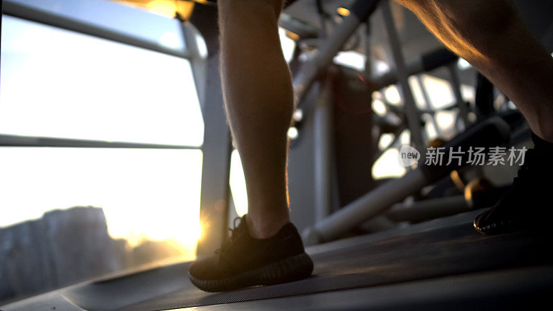 运动员双腿在跑步机上行走，下班后进行日落训练，缓解压力