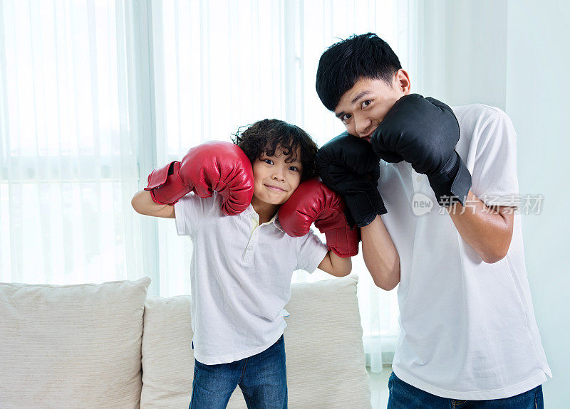 父亲和儿子戴着拳击手套做鬼脸