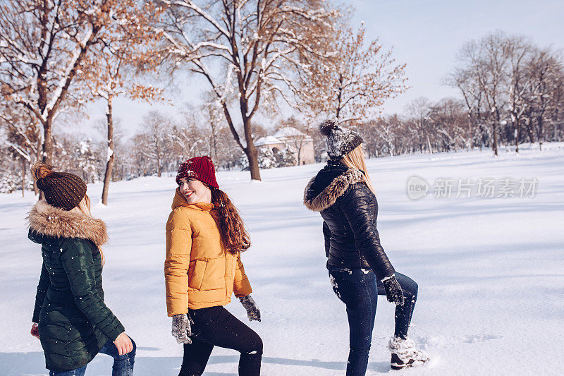 年轻的女友们在阳光明媚的冬日里在山上享受自由，在阳光明媚的日子打雪仗。