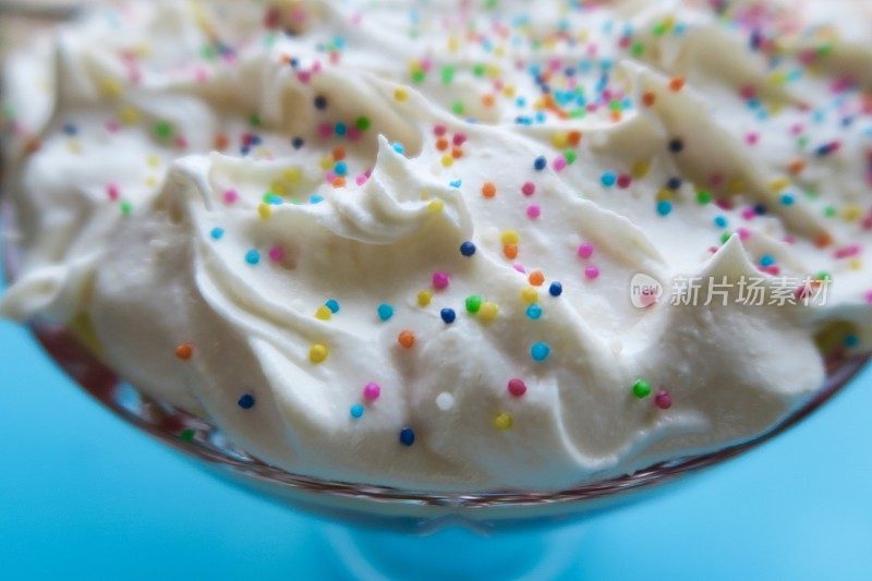 鲜奶油上点缀着五颜六色的彩虹蛋糕，蛋糕上点缀着海绵蛋糕和草莓果冻