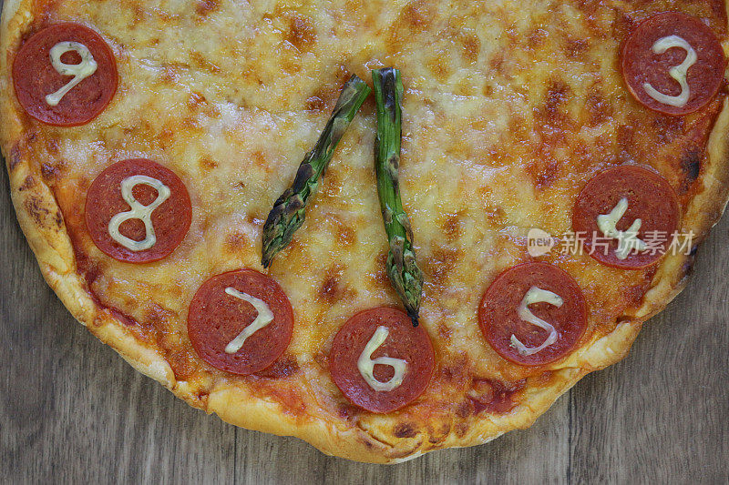 这是一个自制的披萨钟，上面有意大利辣香肠片、马苏里拉奶酪和芦笋作为时钟指针，显示时间是七点半。这是意大利披萨餐厅为孩子们的生日聚会提供的儿童披萨钟