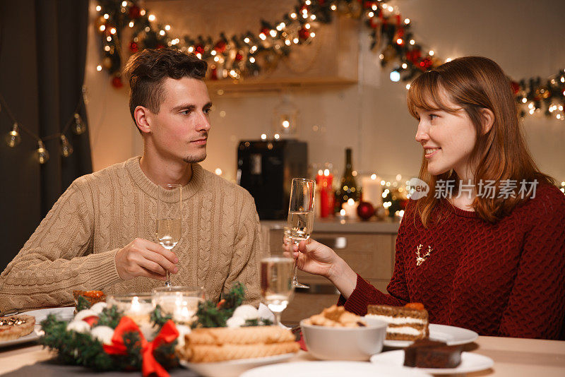 一对年轻夫妇在温馨的家里庆祝圣诞节。他们在平安夜喝香槟。