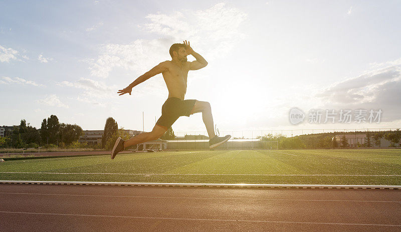 日出时，年轻人在体育场的运动跑道上慢跑和跑步。田径跳远项目