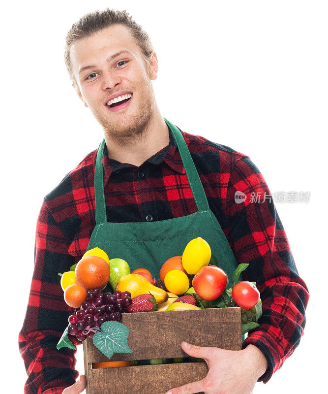 白人男性农民站在白色背景，穿着围裙，拿着水果